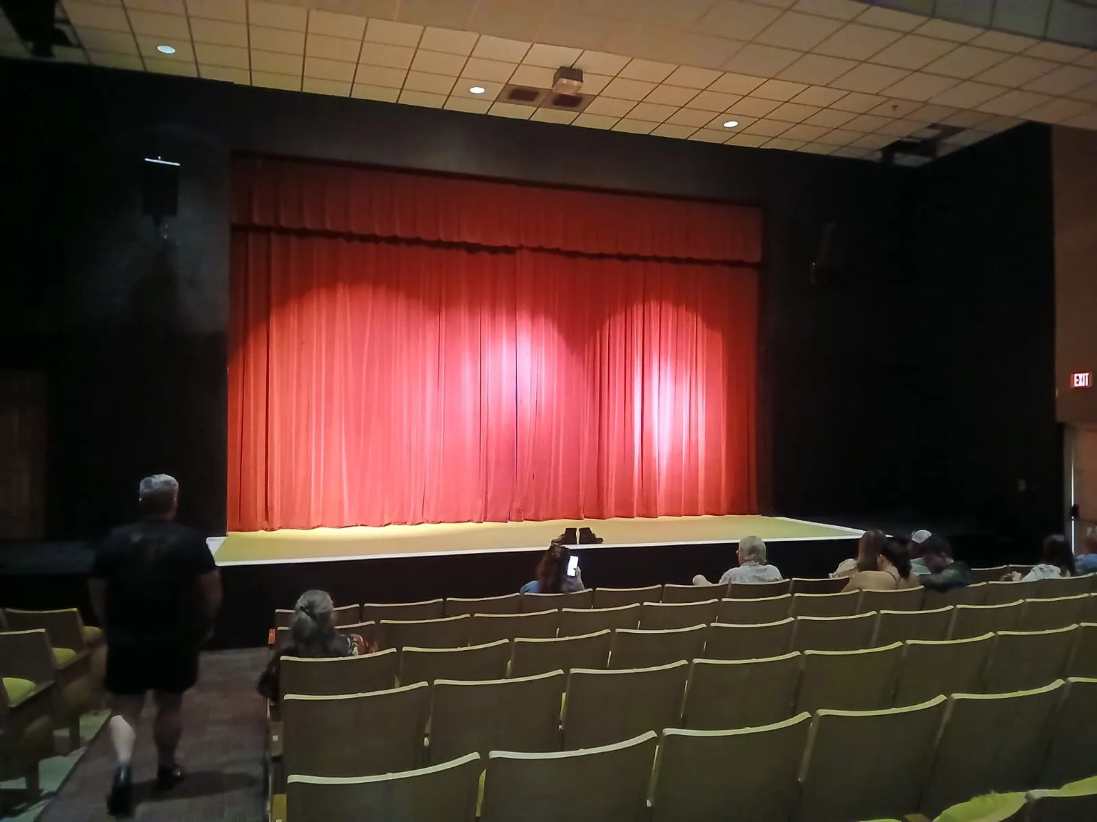 A wide shot of the Spyker Theater stage with its red curtains and empty seats.